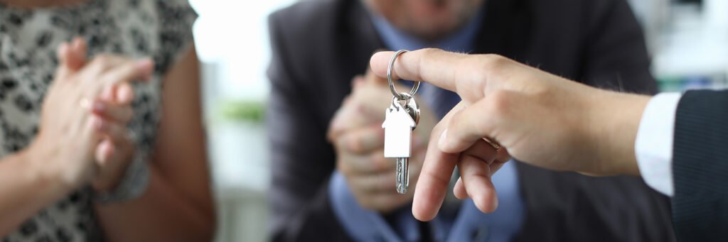 Imagen de Marido y mujer reciben la llave del apartamento del vendedor en primer plano de la oficina